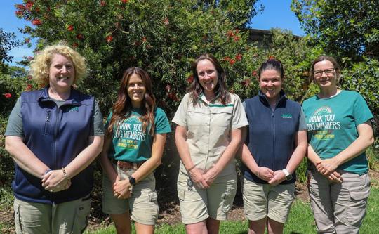 A team of five Zoo employees stand in a row smiling.