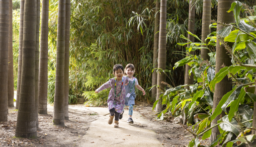 Two children with lanyards running through the bamboo forest.