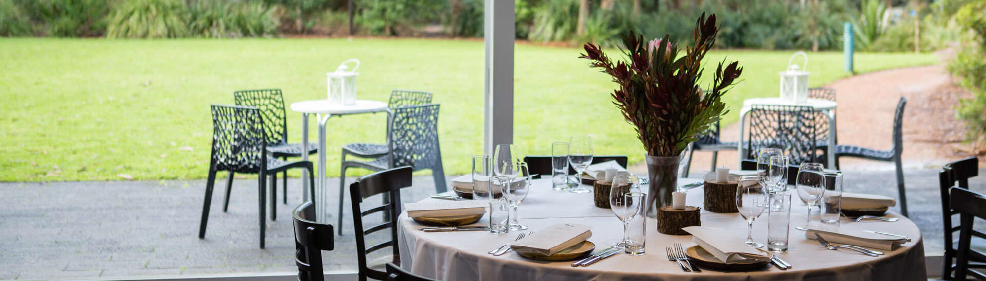 View of Brolga Room, set up for function with one dining table, eight chairs and two outdoor tables with four chairs.
