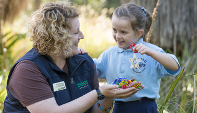 A Student with a ZV Educator, holding up her Beads for Wildlife craft creation.