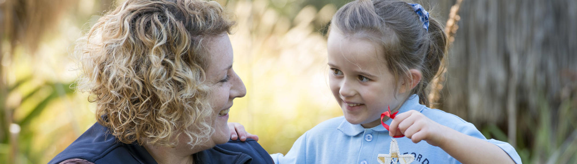 A Student with a ZV Educator, holding up her Beads for Wildlife craft creation.