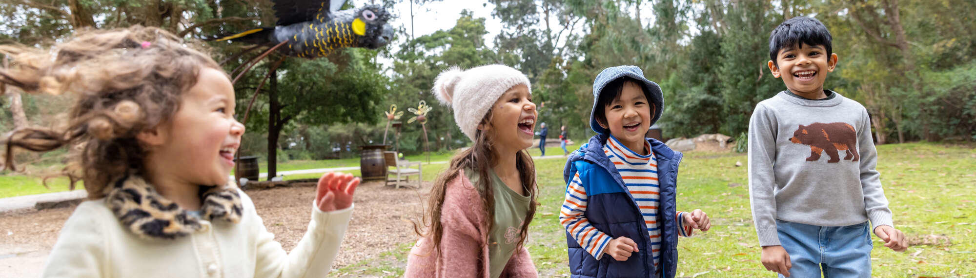Children Marketing Shoot with four enthusiastic young guests, all facing right with the Cockatoo statue behind them.