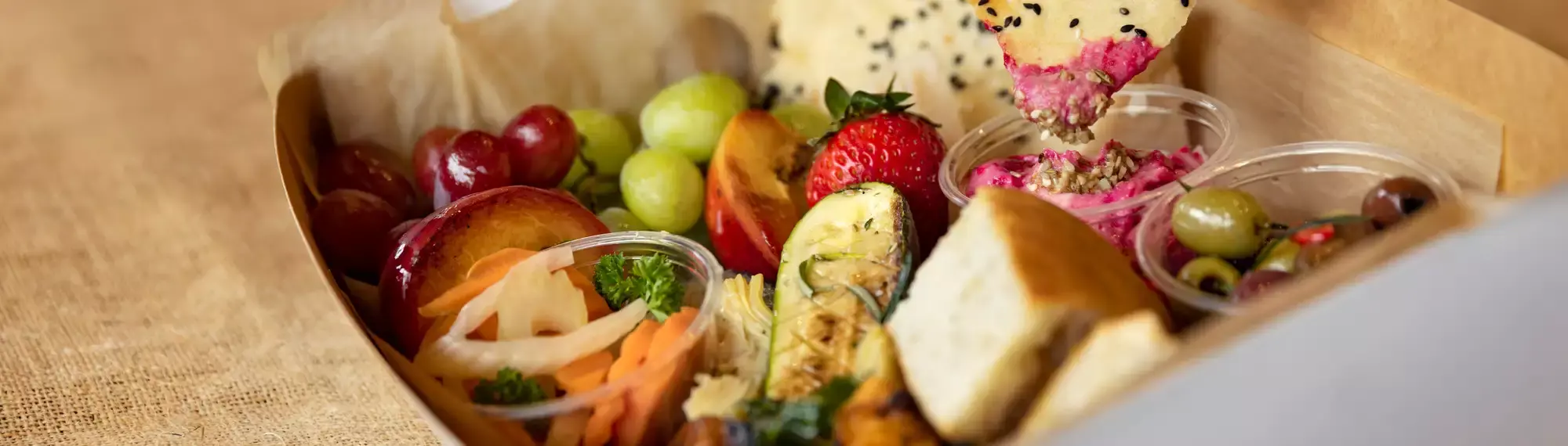 Close up photo of fruit, dips and bread in a box.