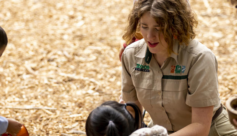 A Keeper interacts with four young guests in the bark-laden Adventure playground.
