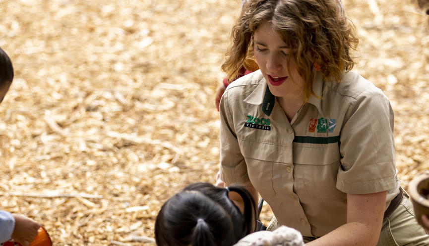 A Keeper interacts with four young guests in the bark-laden Adventure playground.
