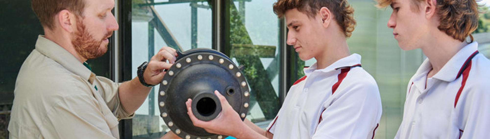 Two high school students with Melbourne Zoo educator investigating an object.