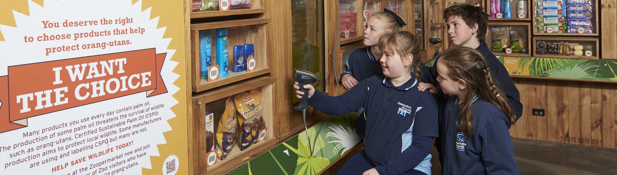 Four school students scan items in Melbourne Zoo's Zoopermarket.