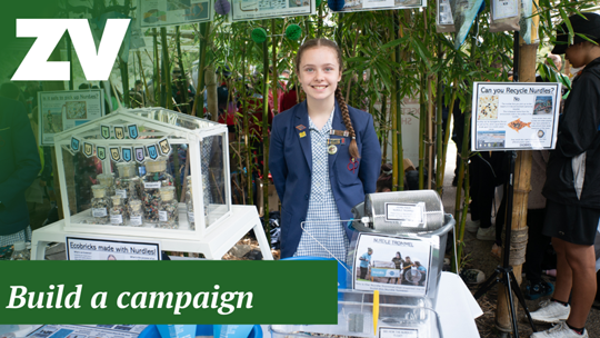 "Build A Campaign": A school student stands smiling behind her craft School showcase.