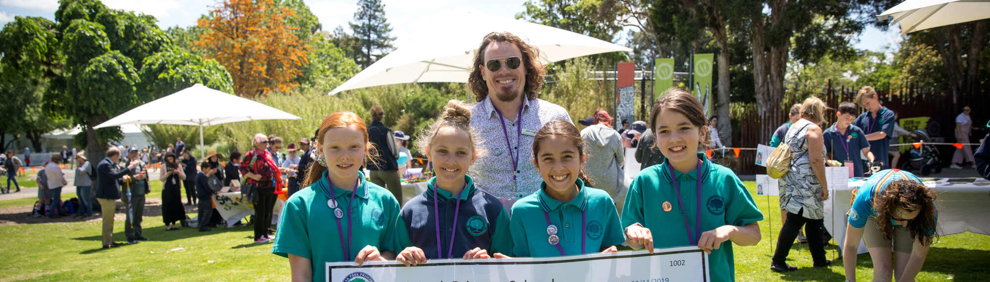 Four students and their teacher posing, as they hold a cheque at the Fighting Extinction Schools Showcase.