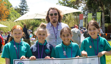 Four students and their teacher posing, as they hold a cheque at the Fighting Extinction Schools Showcase.