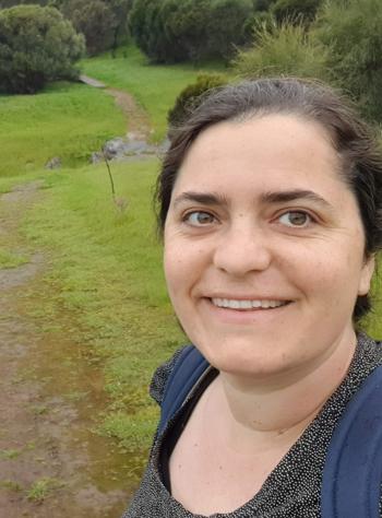 Officer Emily taking a "selfie" in a wind-swept forest clearing,