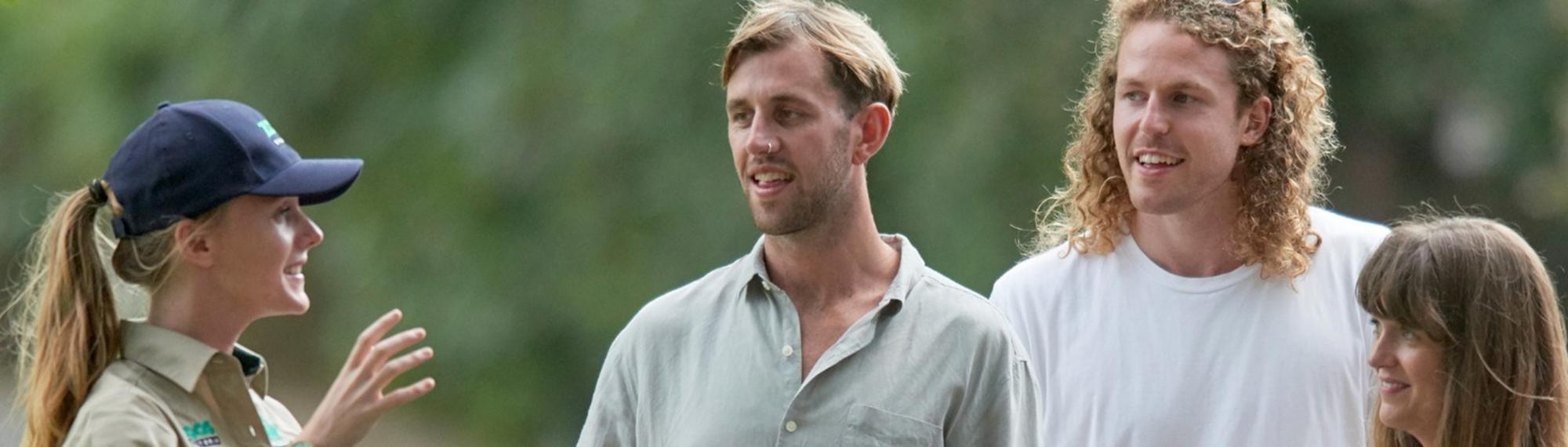 A Keeper, on the left, speaks to three guests on the right.