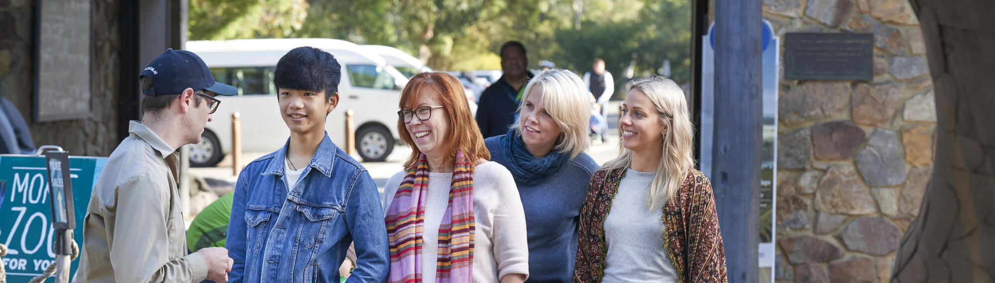 A Zoo member of staff greets four people as they enter through Healesville Sanctuary's entrance.