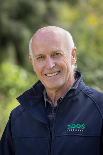 Portrait of Chris Banks, smiling to the camera in front of a leafy backdrop.