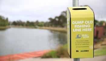 A bin to recycle old fishing line placed in front of a river