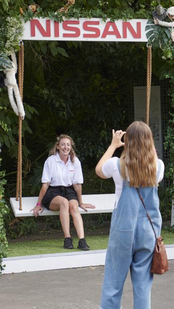 one woman taking photo of a friend who is seating on a Nissan swing chair