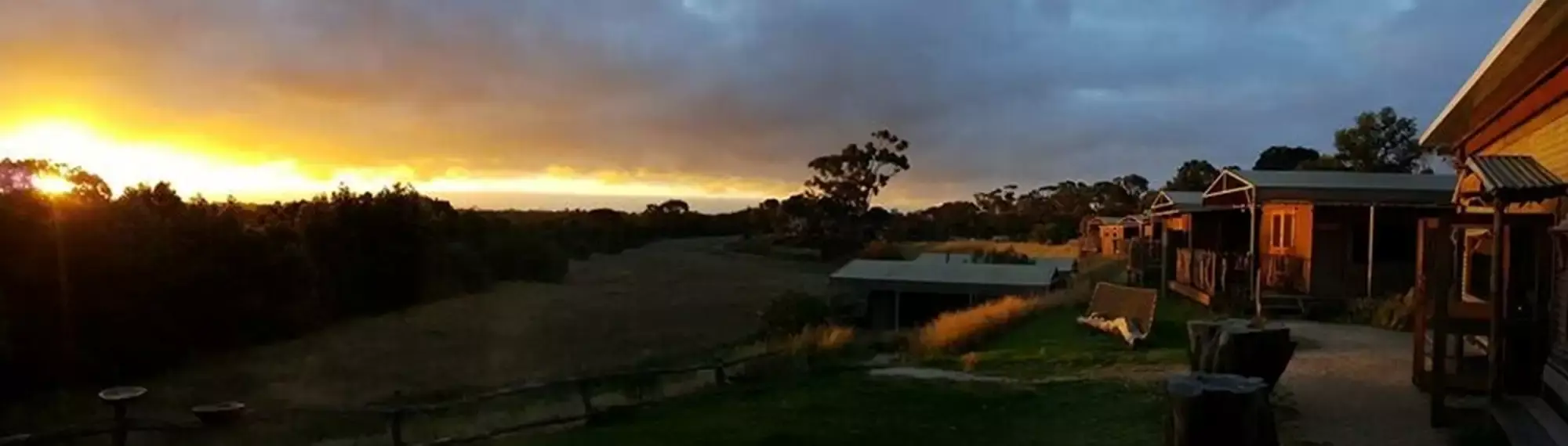 A number of huts overlooking a valley at sunset.