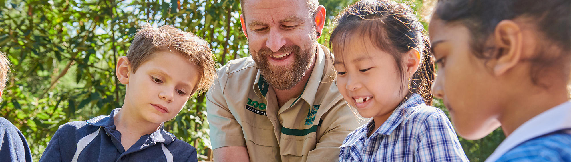 Keeper hosting a talk with four young students (one off frame to the left), all looking downward.