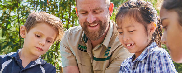 Keeper hosting a talk with four young students (one off frame to the left), all looking downward.