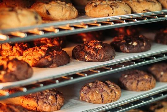 Close-up of assorted cookies on three heated racks.