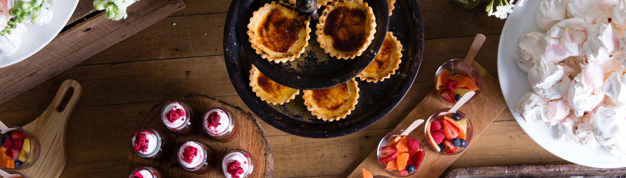 Top down view of various pastries and confections on wooden boards, all on a wooden table.