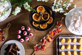 Top down view of various pastries and confections on wooden boards, all on a wooden table.