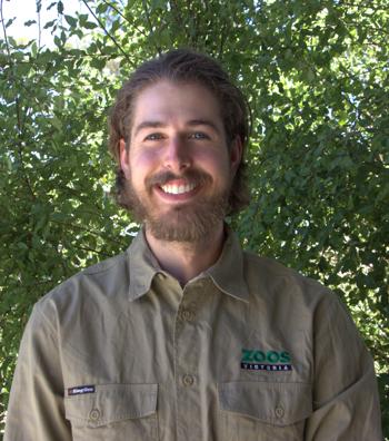 Portrait of Keeper Aaron, in front of a leafy backdrop.