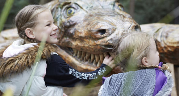Two kids playing at Healesville Sanctuary, with Megalania (the wood-carve statue) in the background.