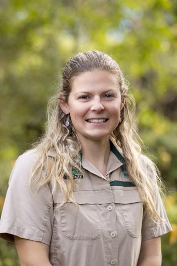 Veterinary Doctor Jessica Thomas, smiling to the camera against a green, leafy backdrop